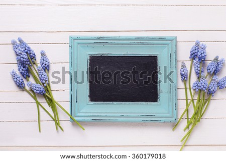Spring blue muscaries flowers and empty blackboard for text on white painted wooden table. Selective focus. Place for text.