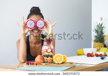Woman smiling with a tropical fruit salad, being playful covering her eyes with dragon fruit Royalty-Free Stock Photo #360191873