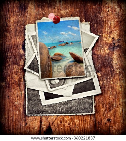 pile of old vintage photographs on a wooden background with on top a colorful image from   big boulders at a tropical coastline with turqiouse seawater