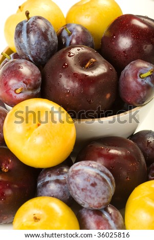 A variety of plums and pluots in a bowl