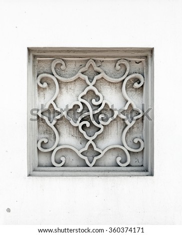 A vintage stone mason window frame with abstract star and curvy symbol pattern.
