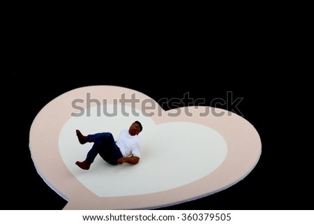 miniature of a lonely man sitting on a heart shaped bench