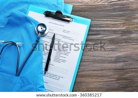 Medical stethoscope, clipboard and coat on the table