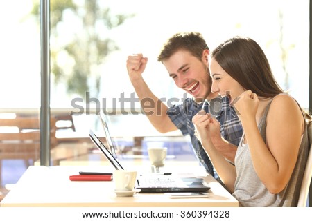 Group of two young euphoric students watching exam results in a laptop in a table of an university campus bar Royalty-Free Stock Photo #360394328