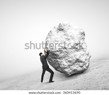 businessman pushing stone up on hill
