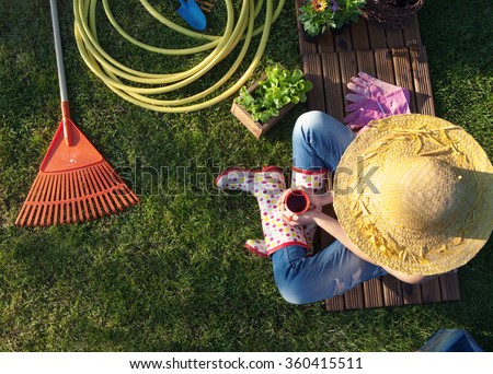Woman having a coffee break while working in the garden Royalty-Free Stock Photo #360415511