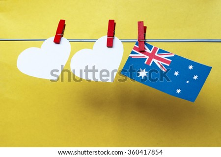 White two hearts and Australian flag hanging on pegs ( clothespin ) on a line against a yellow background. Space for text, Australia concept