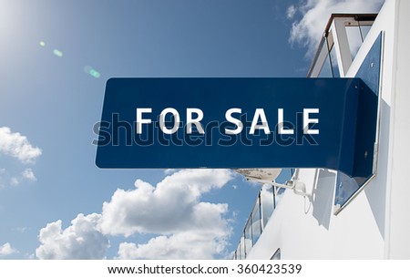 Real estate sign with text: "For Sale"
Modern building with blue sky background.
