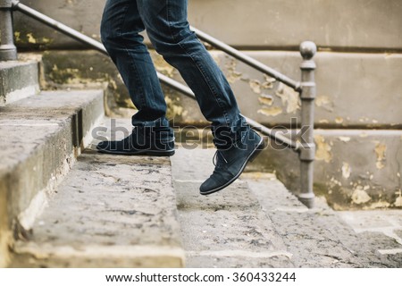 Close-up of man's shoes walking upstairs Royalty-Free Stock Photo #360433244