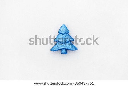 Minimalistic photo of blue toy tree on real snow at winter day.