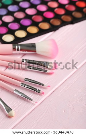 Makeup brush set with palette on a pink wooden table