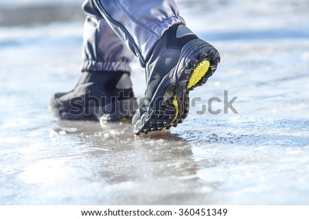 male or female winter boots walking on snowy sleet road Royalty-Free Stock Photo #360451349