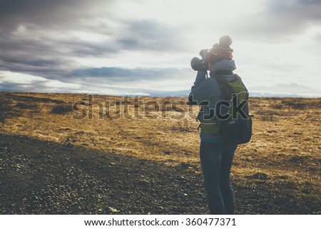 Back view of woman wearing winter clothes taking pictures on sunset in Iceland.