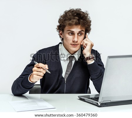 Successful businessman going to make a call by cell phone while working with PC computer on gray background / depression and crisis concept