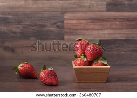Fresh strawberries in a bamboo bowl on a wooden background