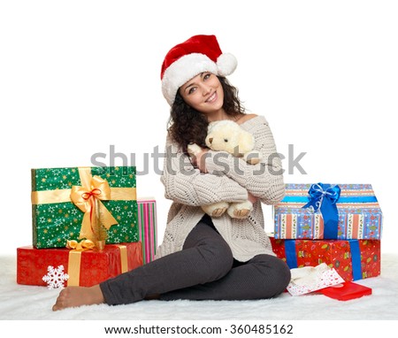 beautiful young girl in santa hat with teddy bear toy and gift boxes, white background