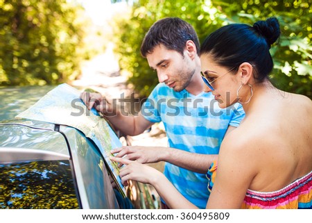 Young travelers looking at a map near the car