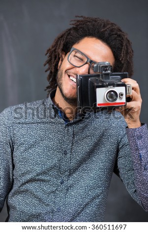 Portrait of a smiling afro american man making photo on retro camera on chalkboard
