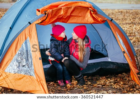 Happy mother and her daughter posing sitting in a tent