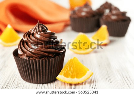 Chocolate cupcakes served with orange on table