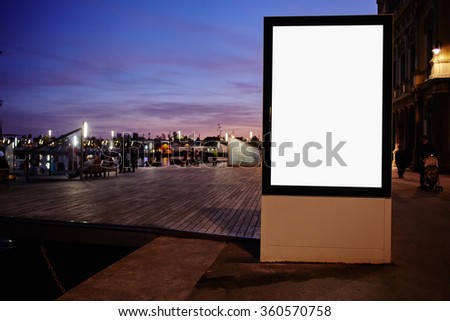 Illuminated blank billboard with copy space for your text message or promotional content,public information board against sunset sky,mock up in urban setting at night,empty banner in metropolitan city
