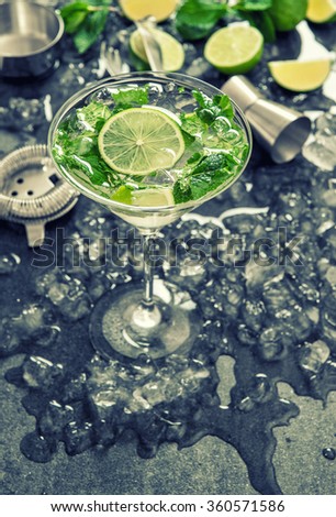 Cocktail with lime, mint and ice. Bar drink accessories. Vintage style toned picture
