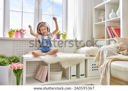 little girl with headphones at home. child girl listening to music.  Royalty-Free Stock Photo #360595367