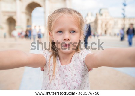 Adorable little girl taking selfie with mobile phone outdoors in