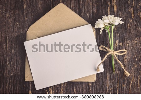 Blank white greeting card with brown envelope and wither Mum flowers on wooden table with vintage and vignette tone Royalty-Free Stock Photo #360606968
