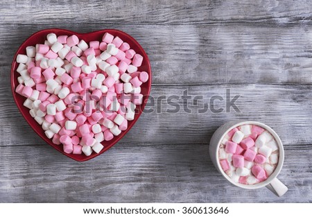 On a black wooden table in rustic style red heart-shaped plate with marshmallows, there is an empty space for your text, congratulations on Valentine's Day
