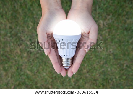 LED Bulb with lighting on hand with nature background Royalty-Free Stock Photo #360615554