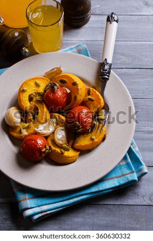 Slices of roasted pumpkin with garlic and tomato on a wooden background. Selective focus.