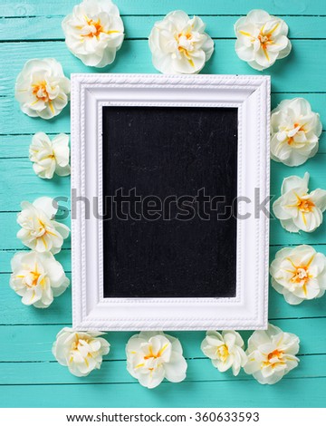 Fresh  spring  white narcissus  and empty blackboard on green painted  wooden background. Selective focus. Place for text.