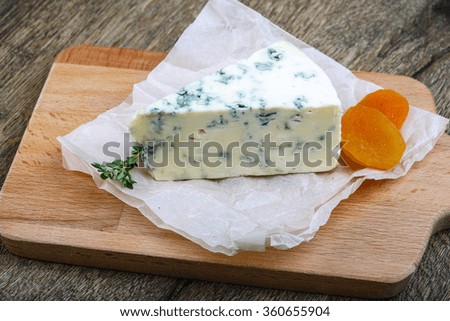 Roquefort cheese with thyme and dry apricot on the wood background
