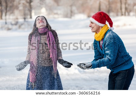 Happy couple having fun ice skating on rink outdoors. Throwing snow together. Winter sport and leisure concept. Love and fun in wintertime.
