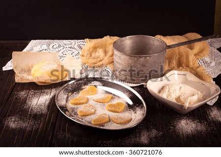 cooking biscuits in the shape of a heart on a wooden brown background, flour, rolling pin, the concept of Valentine's Day