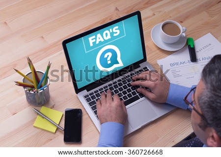 Man working on laptop with FAQ'S on a screen
