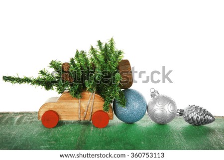 Wooden toy car with Christmas tree  and toys on a table over white background