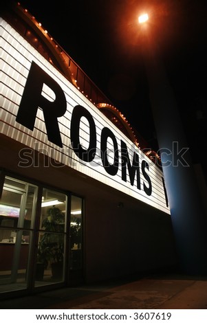 Shining neon sign "Rooms" on a hotel at night.