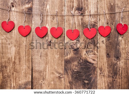 Love concept. Hearts hanging on a string, shot on wooden background