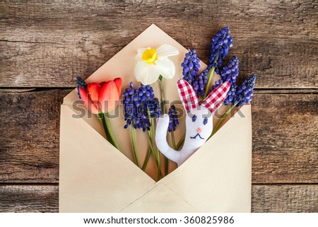 Happy easter card with easter bunny, easter rabbit spring flowers in retro/ vintage envelop over grunge wooden background