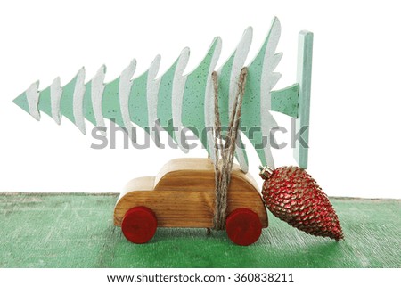 Wooden toy car with Christmas tree and cone on a table over white background