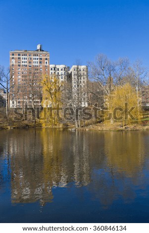 Central Park picture with a lake, manhattan buildings and trees. All reflecting on lake. Tree without foliage.