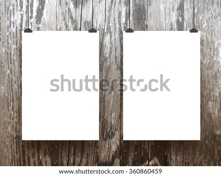Close-up of two hanged paper sheets with clips on brown wood background