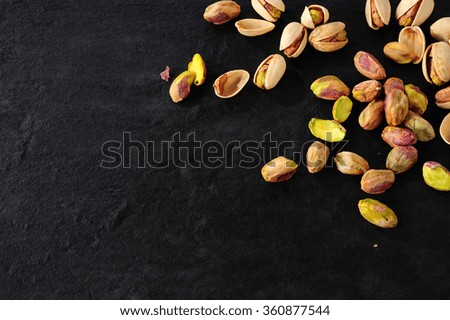 pistachios over dark slate background Royalty-Free Stock Photo #360877544