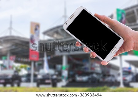 Girl use mobile phone, blur image of automobile dealers-used cars as background.