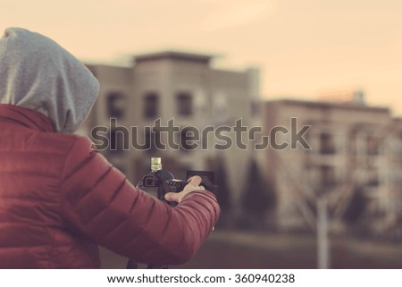 Photographer with a camera taking pictures of a city with blurred background in warm matte film finish