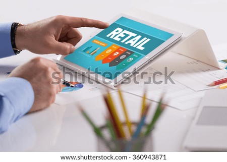 Businessman working on tablet with RETAIL on a screen