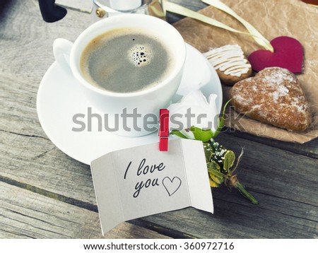 Heart shaped  cookies (big and small as couple), cup of coffee, bouquet of flowers decoration on old wooden table. sunny morning.I love you message. Romantic or  Valentine's Day Breakfast. Toned image