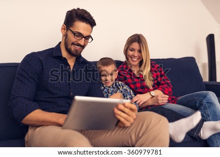 Shot of mom and dad watching cartoons on tablet with son.